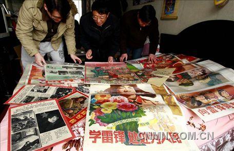 3月1日，房冠龍（中）在家中整理關(guān)于雷鋒的宣傳海報(bào)。